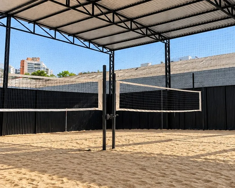 Quadra de areia coberta da KR, com rede de vôlei e estrutura metálica